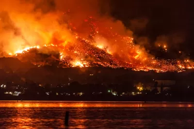 Wildfire burning at night on hillsides next to Lake Elsinore, California.