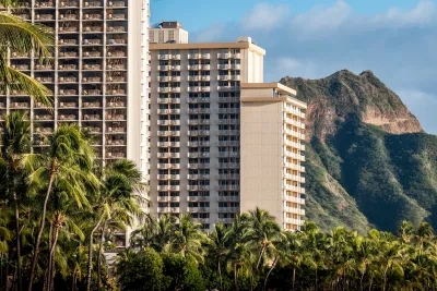 High-rise apartment buildings in Waikiki, Hawaii with steep green mountains in background.
