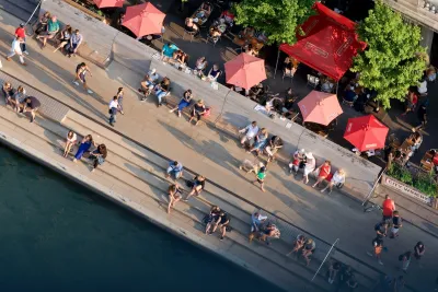 Bird's eye view of people and red sun umbrellas on Chicago riverwalk.