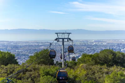 View of aerial tram cars at Oakland Zoo with Oakland, California neighborhoods in background.
