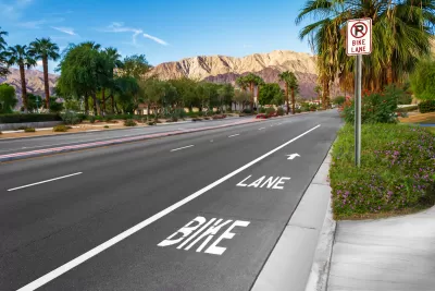 Marked bike lane on wide asphalt street with palm trees and Los Angeles mountains in background.