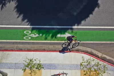 Bird's eye view of green painted bike lane with one cyclist.