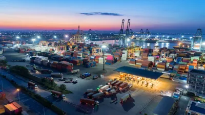 Large port with containers, cranes, and ships at dusk.