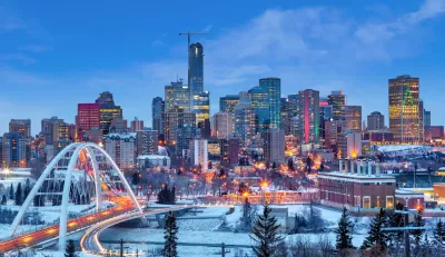 Dusk view of downtown Edmonton, Canada skyline with arched white bridge in foreground