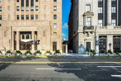 View from street of two neoclassical buildings with narrow alley between them.