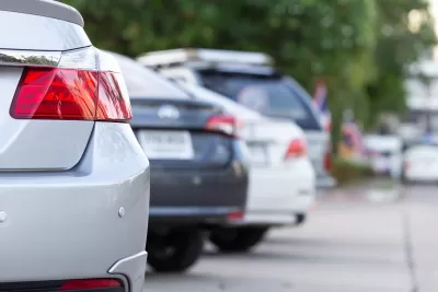A view of the rear of four cars parked in angled spaces.