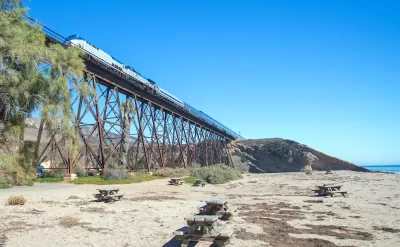 Amtrak train passing over tall trestle bridge on California coast at Gaviota Beach.