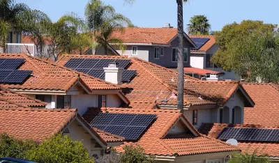 Photovoltaic solar panels on red-tile rooftops in California neighborhood.