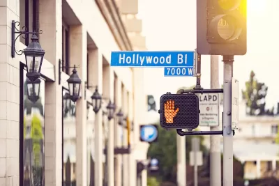 Close-up shot of Hollywood Blvd street sign and pedestrian crossing signal with red 'Don't walk' hand lit.