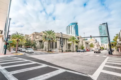 View of empty zebra crosswalk at intersection in Orlando, Florida with glass towers in background.