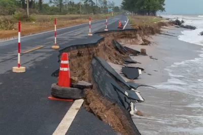 Asphalt road on coast with collapsed segments from erosion.