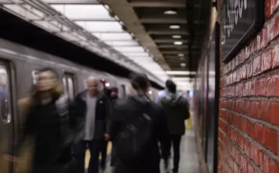 Busy New York City subway platform with blurred people walking in and out of trains and close-up on red brick wall on right.