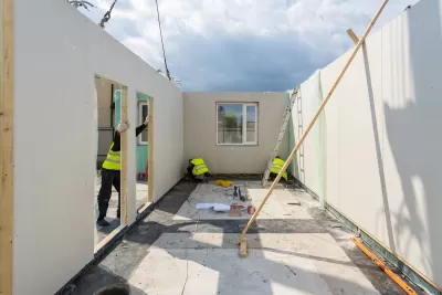 Workers assembling a modular housing unit.