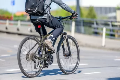 Close-up of person on bike wearing backpack riding on city street.