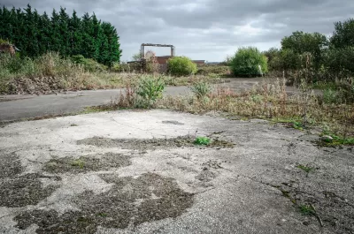 Vacant lot with overgrown concrete foundation