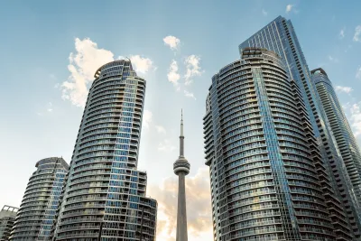 Tall modern condo buildings on both sides of CN Tower rising in middle.