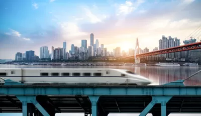 High-speed rail train passing on bridge with Chongqing, China skyline in background.