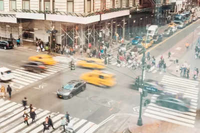 Aerial view of busy NYC crosswalk with pedestrians and blurred traffic.
