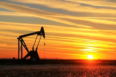 Oil pumpjack in a field at sunset.