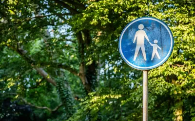 Blue sign with white sillhouettes indicating parent and child crossing street.