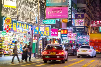 Cars and pedestrians on Hong Kong street at night.