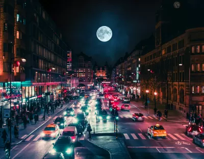 View of busy street at night with full moon in background in Stockholm, Sweden