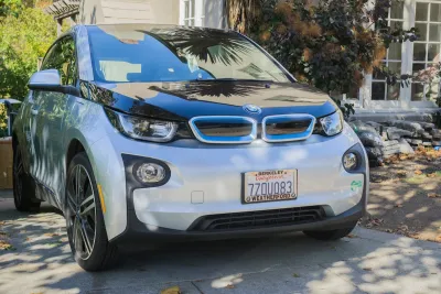 Silver electric BMW car parked in driveway of home in Oakland, California.