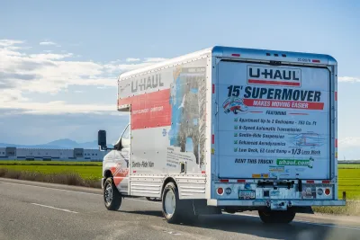 U-Haul truck on road with blurred grassy roadside in background.