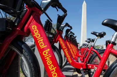 Close-up of red Capital Bikeshare bikes with Washington Monument in background.