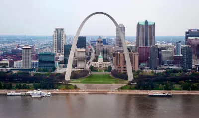 View of the Gateway Arch with Mississippi River in foreground and St. Louis skyline in background.