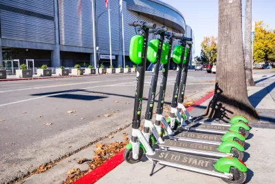 Several Lime e-scooters lined up next to curb on a sidewalk in San Jose, California.
