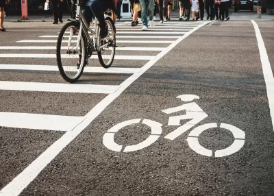 Low angle of pedestrians and a bicycle crossing the street at an urban crosswalk.