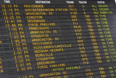 Close-up of old-fashioned trains departure board with yellow text on black background in Boston, Massachusetts train station.