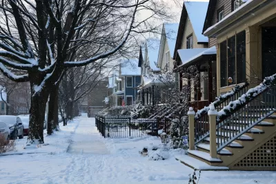 Snow covers a sidewalk and small homes on a Chicago street