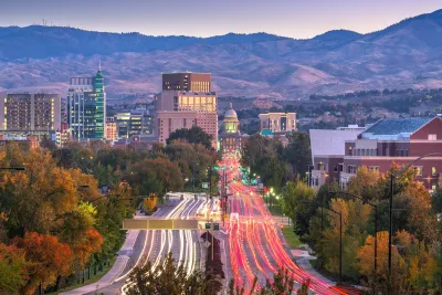 View of wide street in downtown Boise, Idaho with state capitol visible at end of street and blurred traffic going both directions at dusk.