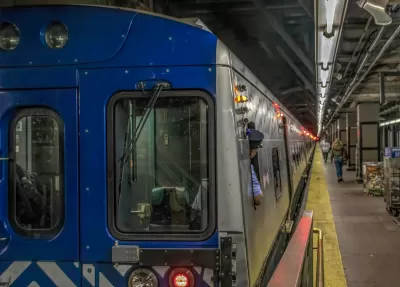 New York City subway train at station with operator looking back toward platform.
