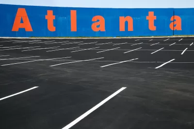 Empty asphalt parking lot with blue wall in background with Atlanta painted in orange letters.