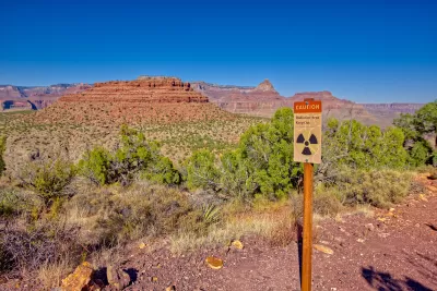 "Radiation Zone, Keep Out" sign on wood post with red Arizona desert mesa in background