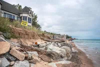 Houses on Lake Michigan shore with yellow "Keep Off Rocks" sign.