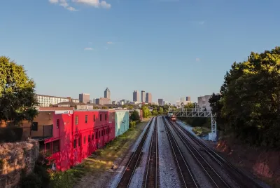 Train tracks with red building on left side and Atlanta high-rises visible in background.