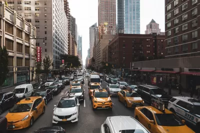Yellow taxis and white cars in traffic on New York City street.