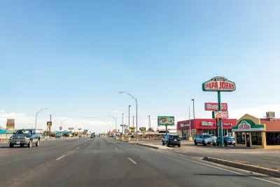Wide multi-lane road in Alamogordo, New Mexico with Papa John's and other fast food restaurants along road.