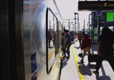 People boarding Los Angeles Metro train on outdoor platform.