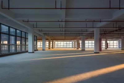 Large empty office building floor with columns and golden hour light.