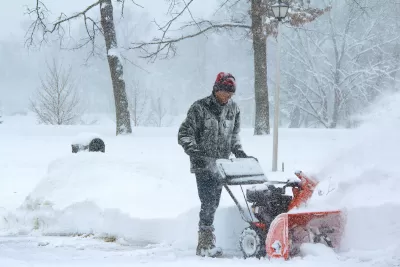 Man using snow plow during snowstorm.