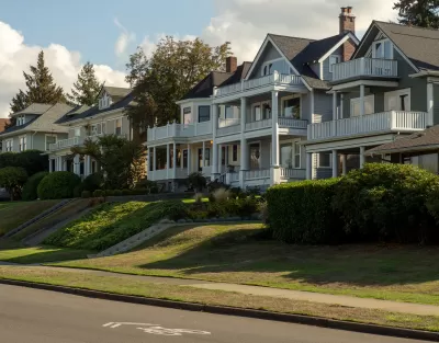 Row of large multistory homes with multilevel porches on the front and a bike lane on the street in front of them.