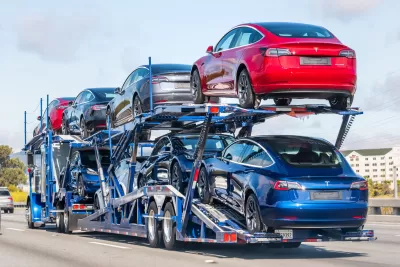 Red, grey, and blue Tesla cars on the back of a truck trailer in Burlingame, California