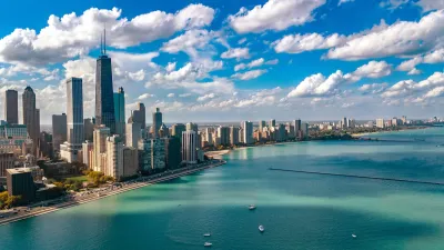 Aerial view of Chicago skyline on bright day with turquoise Lake Michigan in foreground.