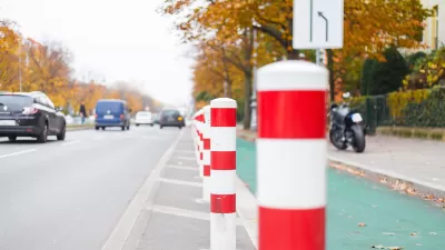 Close-up of white delineators with red stripes denoting green painted bike lane in Berlin, Germany.