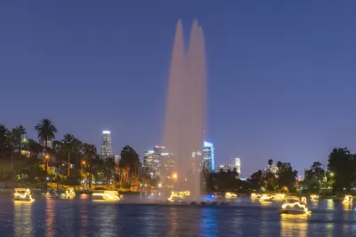 View of Echo Park Lake at night with artesian fountain and illuminated swan paddle boats and Los Angeles skyline in background